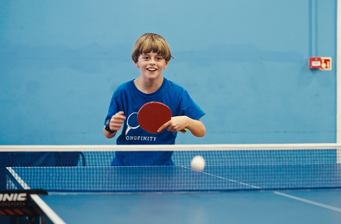 Young Ryan playing table tennis in his Pongfinity shirt