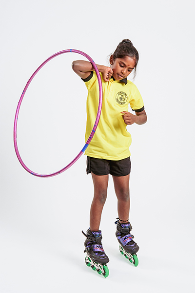 Vaishnavi passing a hula hoop around her body using her elbows while balancing on inline skates