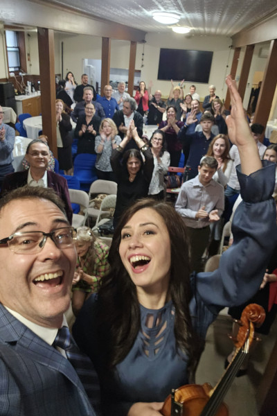 Diana and Stefan taking a selfie with a room full of concertgoers