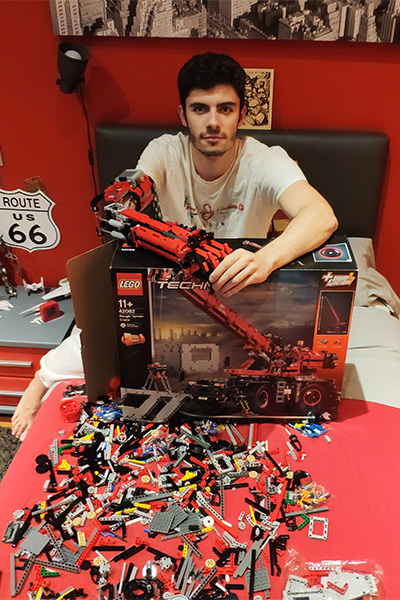 David sitting on his bed surrounded by LEGO