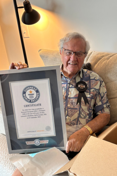 Normand smiling, holding his GWR shirt, with a 96 button