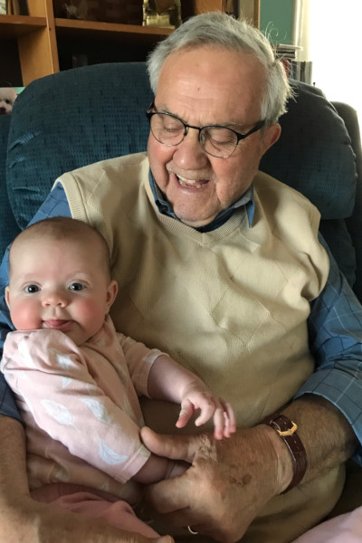 Normand smiling and holding baby Madison as she has her tongue out