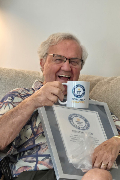 Normand smiling and holding his GWR certificate and a mug
