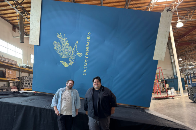 Two creators of the book posing next to the cover
