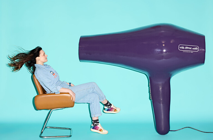 Ruth sat in a chair in front of the largest hairdryer with her hair blowing behind her