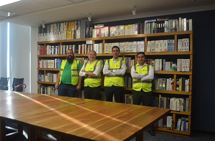 Ariel with three men who helped count his collection standing in front of it on shelves