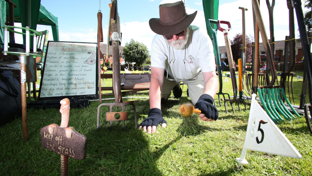 A man banging the ground with a mallet at the Worm Charming Championships