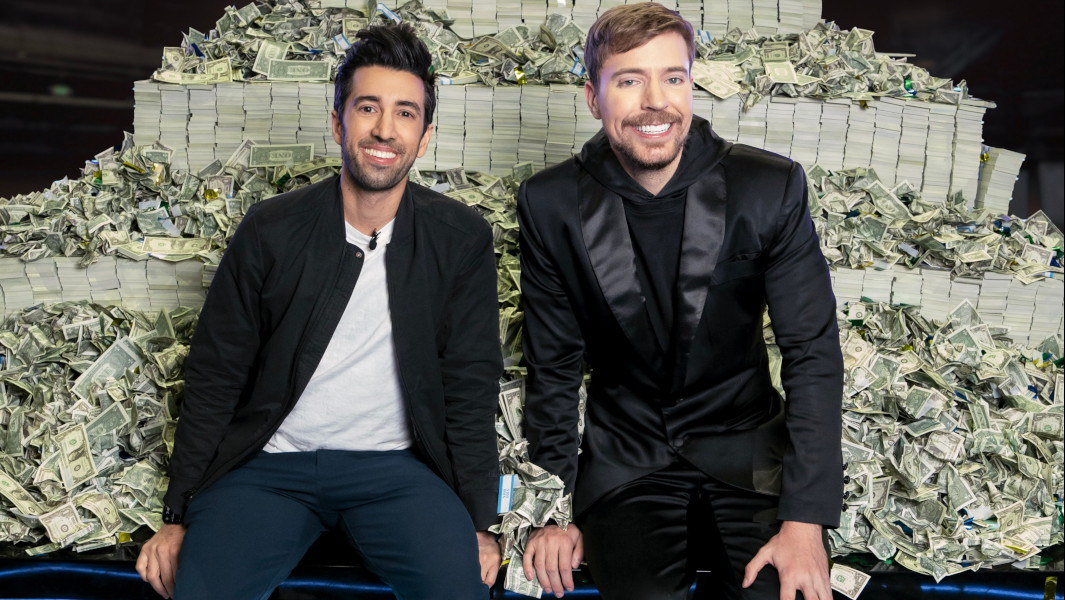 Jon and MrBeast posing in front of a pile of cash