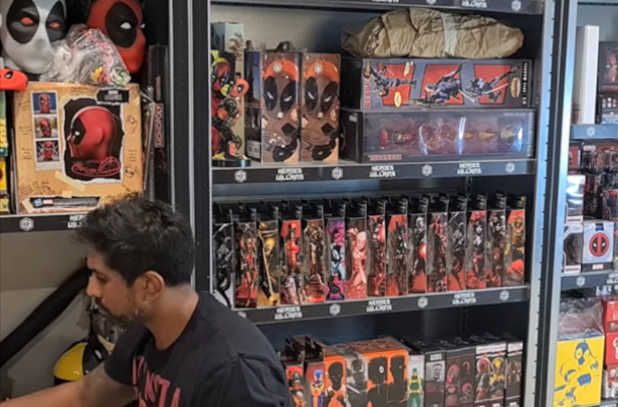 Greg sitting in front of a Deadpool covered shelf