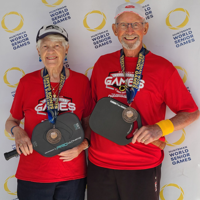 Joyce and her partner posing with their paddles and medals