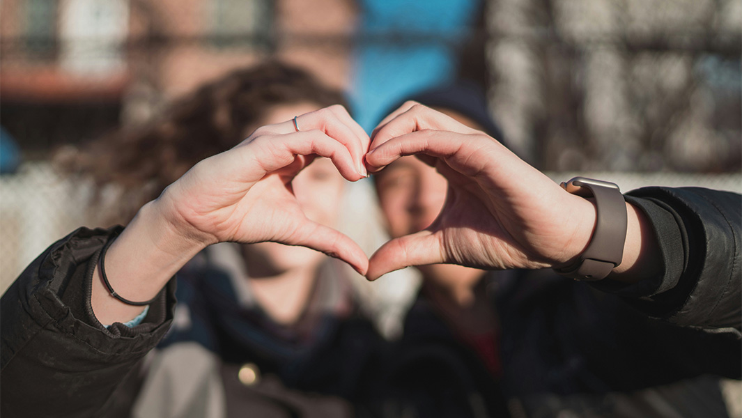 man and woman holding hands together to make a heart
