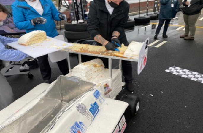 A car cake being cut into pieces 