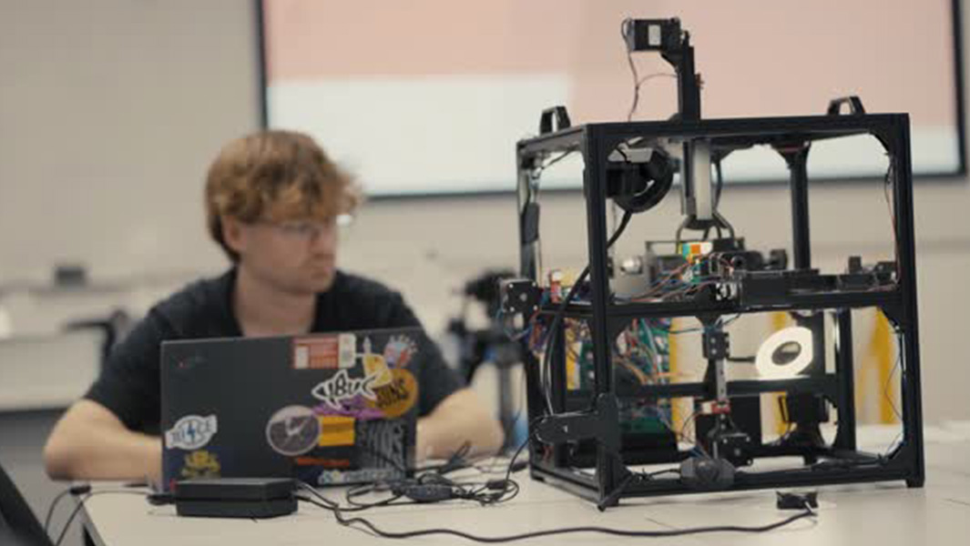 split image of man working on robot and holding solved puzzle cube
