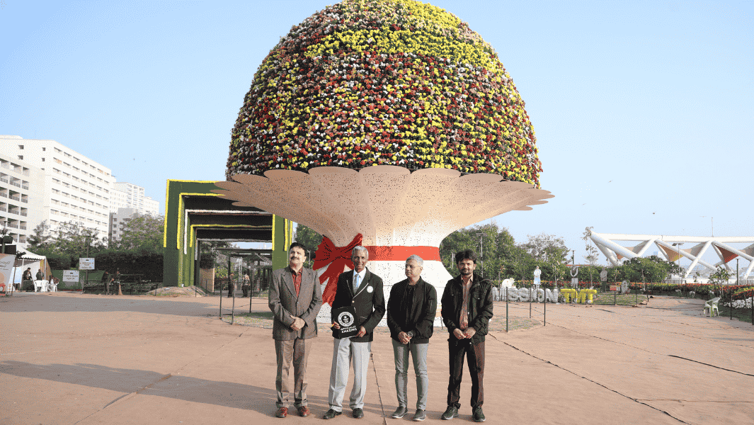 Split image of four men standing next to a large flower installation
