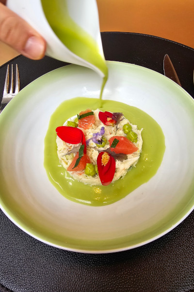 A chef pouring green sauce over a dish