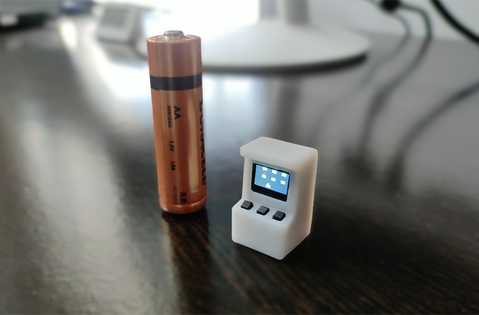 smallest arcade machine next to an AA battery