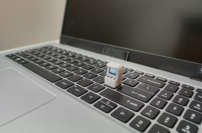smallest arcade machine sitting on a laptop keyboard