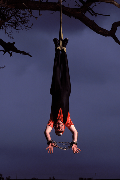 Nick Janson hung upside down with his hands cuffed and smiling