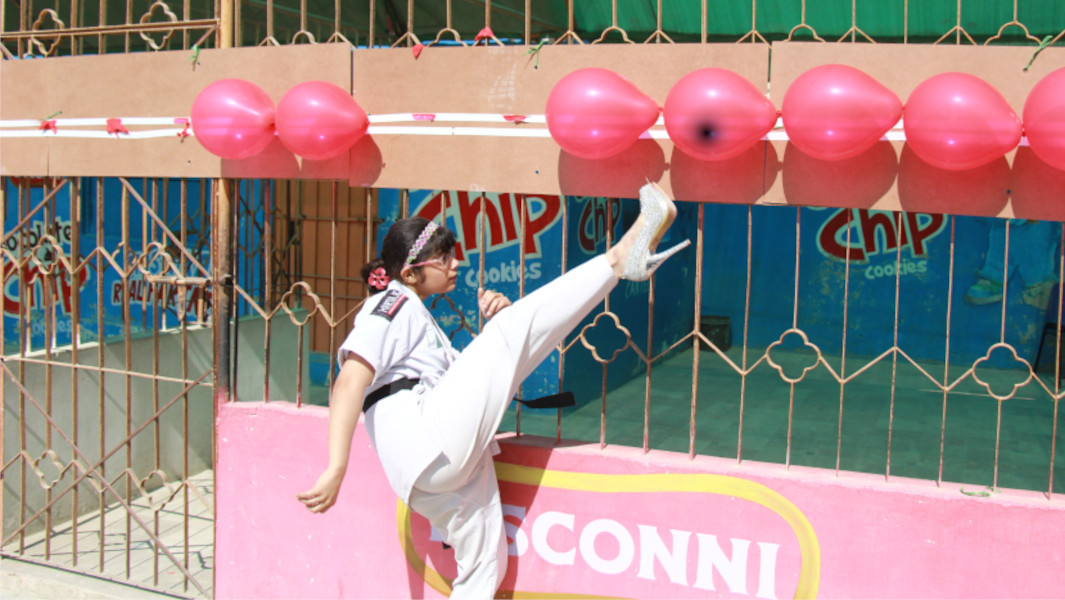 Fatima popping a row of balloons with her heel