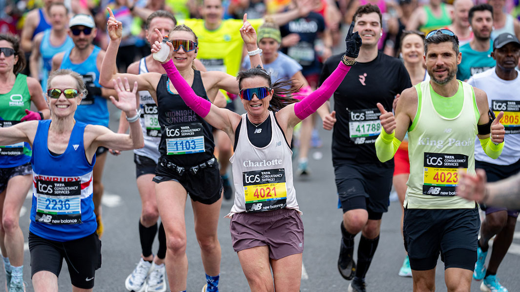 a crowd runs in the london marathon with buckingham palace in the background
