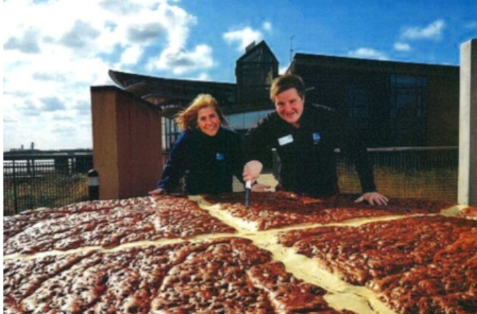 People smiling standing next to the largest hot cross bun ever!