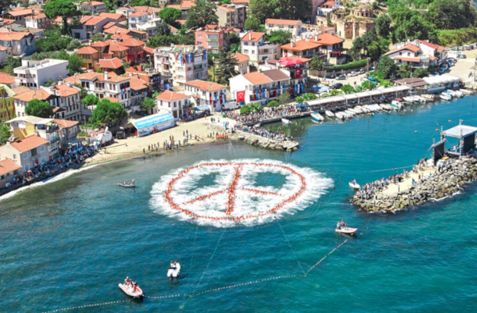 People floating in orange life jackets to make a peace sign