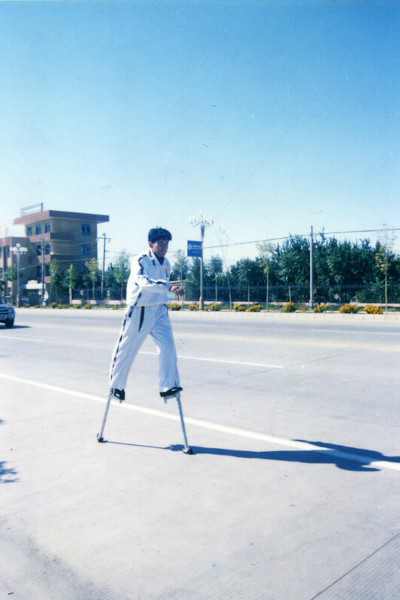Saimaiti walking along the side of the road in stilts