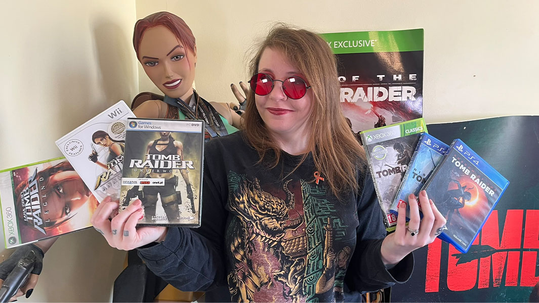Collector holding up some of her Tomb Raider games and wearing red-tinted shades like Lara Croft wears