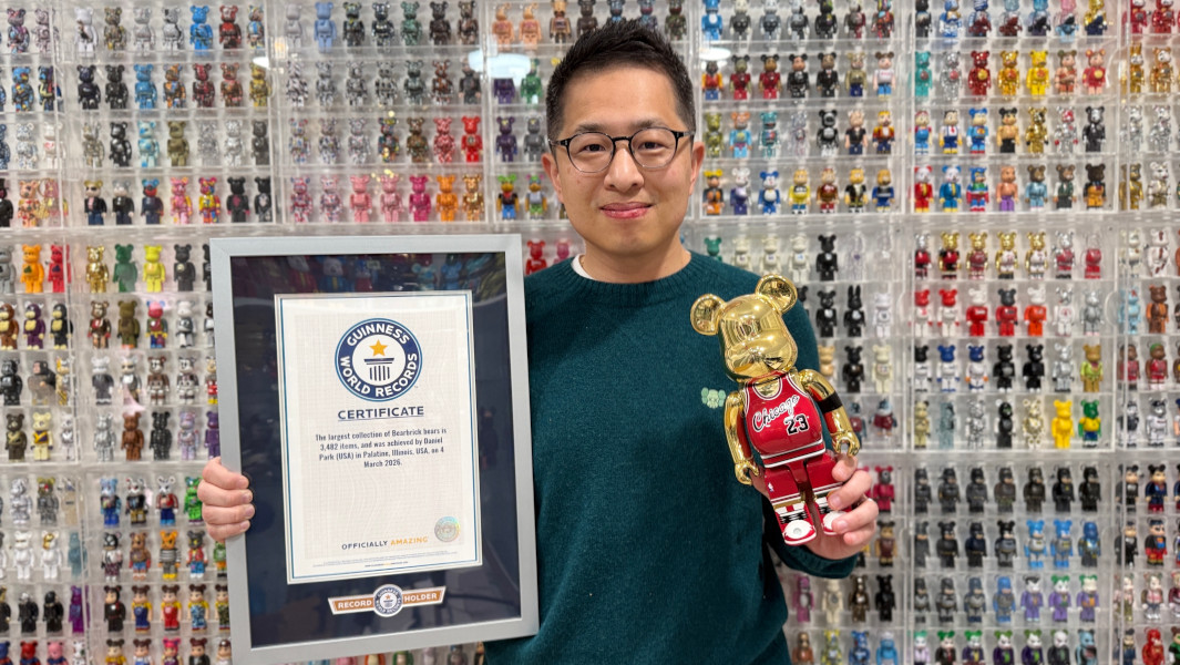 Daniel holding his GWR certificate in front of dozens of Bearbrick bears