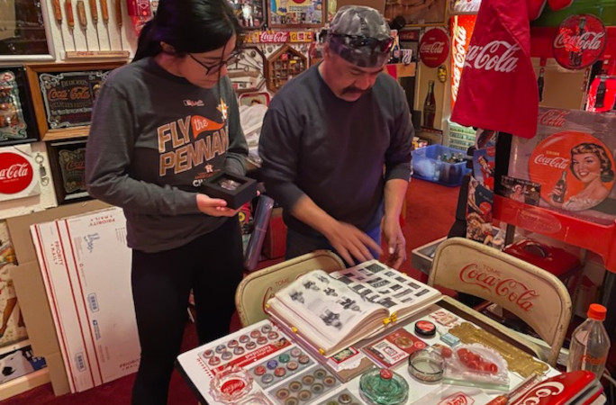 Bardo and Sam flipping through a binder full of merch