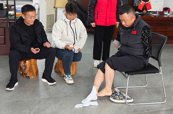 Li pulling socks on with his feet