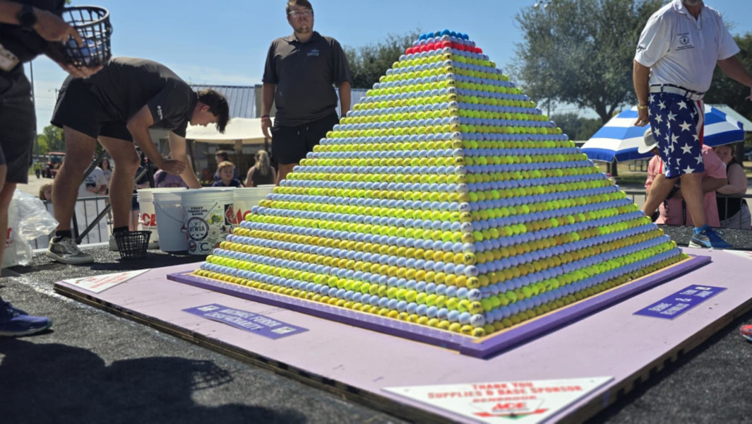 Workers adding balls to the golf ball pyramid