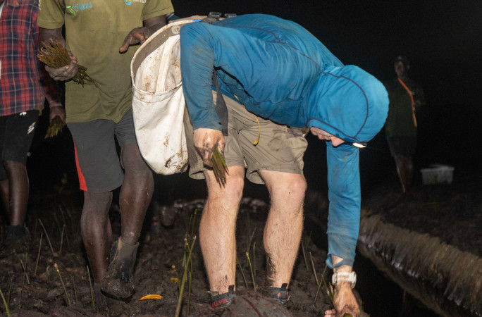Antoine bent over, planting at night