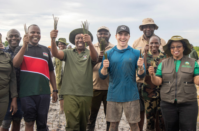 Antoine and his helpers smiling and holding mangroves