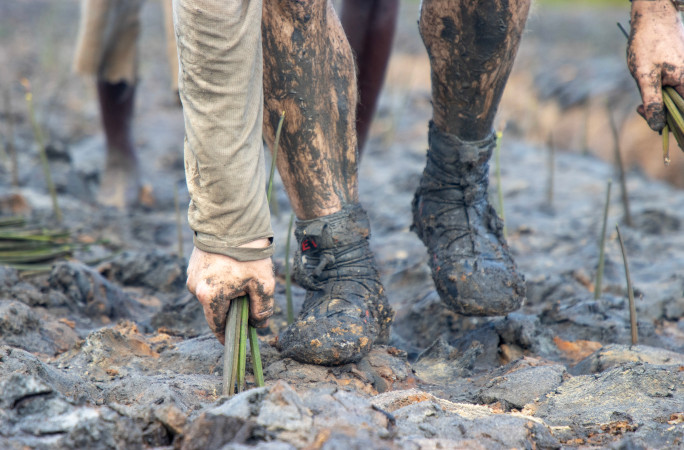 Closeup of Antoine's feet in the mud while planting