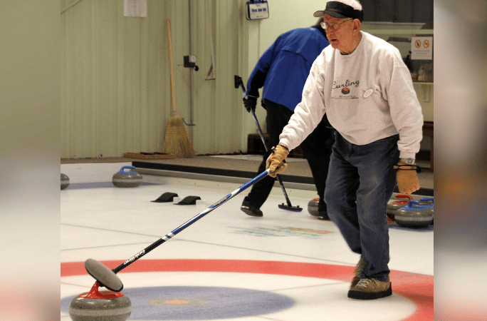 A man playing curling on an ice ring