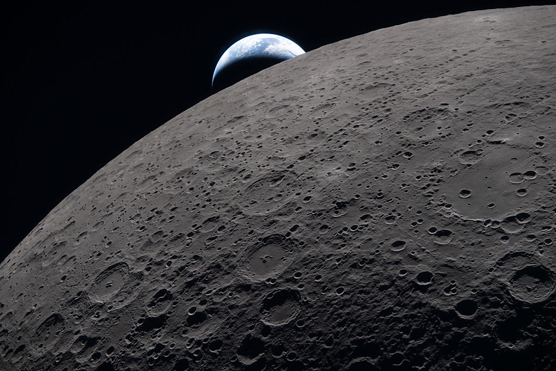 A picture of the Earth appearing from behind the Moon, taken by the crew of Artemis II