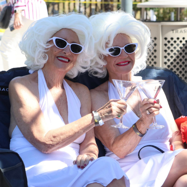 Two people dressed as Marilyn Monroe doing a toast with empty cocktail glasses