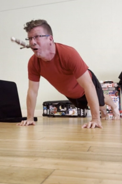 Closeup of Noah doing a pushup with a sword in his mouth