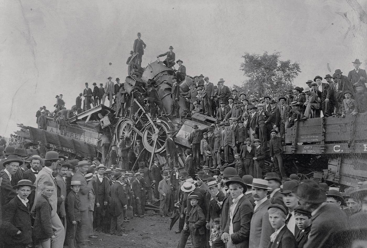 A large crowd climbs over the wreckage of two locomotives