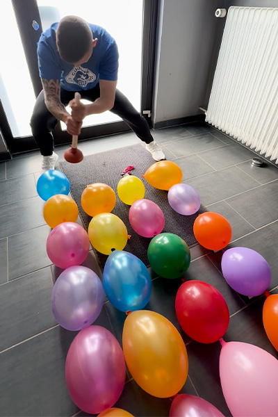 Andre popping balloons with a plunger