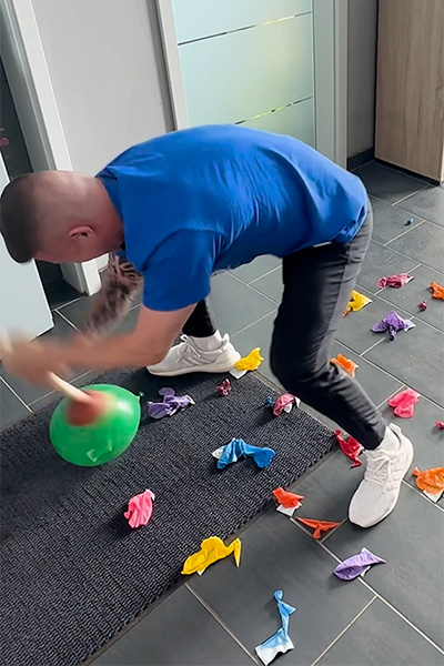 Andre popping balloons with a plunger