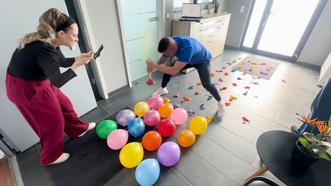 split image of Andre holding up two plungers and using one to pop balloons