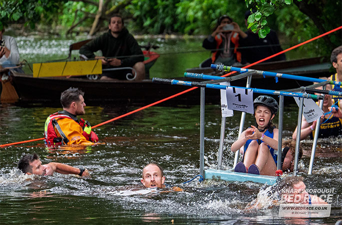 girl screaming while being carried on a bed through water