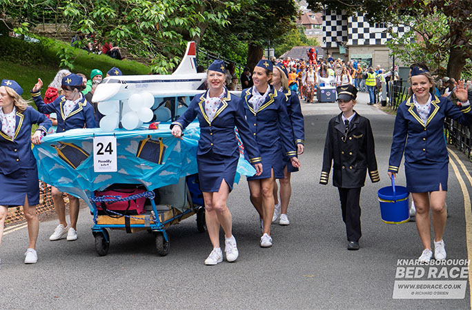 team in the bed race pushing a fake plane and dressed as cabin crew
