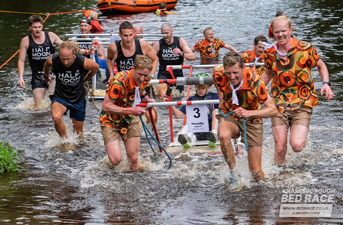 bed race team running out of the water