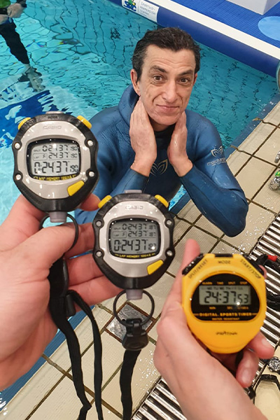 Budimir at the side of the pool with three stopwatches held up in front of him