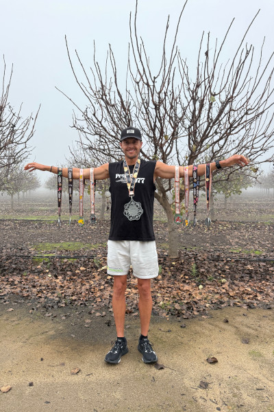Christian holding up all of his race medals