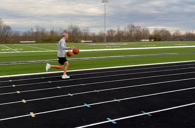 Michael running while dribbling basketballs
