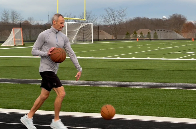 Michael running while dribbling basketballs